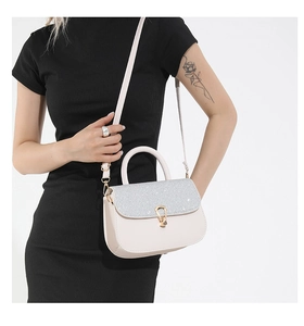 Detail of elegant beige handbag with silver sequin flap and golden U-shaped buckle