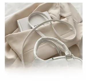 Close-up of white leather handbag with cherry pattern and refined shoulder strap detail