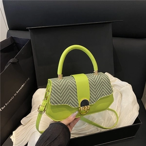 Lime green handbag with woven flap and metallic clasp on an elegant gift box background
