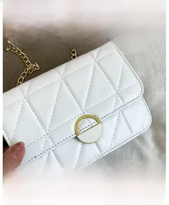 Detail view of white quilted crossbody bag with gold round buckle and chain strap