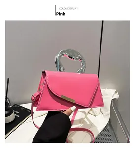 Detail of pink geometric handbag with liquid metal handle and gold buckle accent