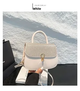 Close-up of white glossy leather handbag with rhinestone flap and gold horseshoe buckle