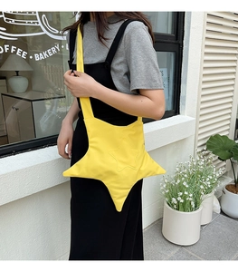Detail view of a bright yellow star-shaped crossbody bag worn with a black dress