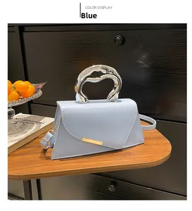 Detail of blue leather handbag featuring unique liquid silver handle and golden bar accent