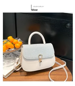 Close-up of a white leather bag with silver glitter flap and gold U-shaped metal clasp