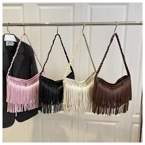 Détail de grands sacs à bandoulière à franges en couleurs rose, noir, blanc et marron