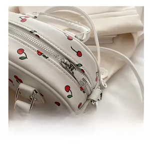 Detail of smooth silver zipper and cherry print on white leather crossbody bag
