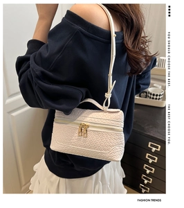 Detail of white woven texture shoulder bag with golden zipper and adjustable strap