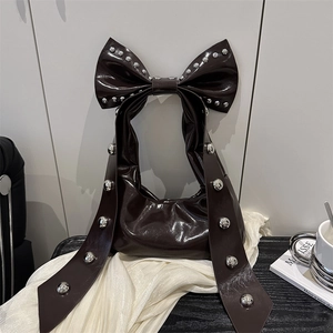 Elegante borsa in vernice scura con fiocco e borchie argentate in un contesto lifestyle