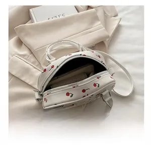 Internal capacity of cherry print round bag showing space for phone and wallet