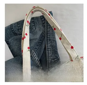 Detail view of corduroy shoulder bag showing cherry print and soft handle craftsmanship