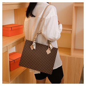 Detail of checkered crossbody bag with silk scarf handle on high-quality store display