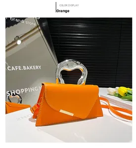 Detail of orange textured trapezoid handbag featuring a unique silver metallic handle