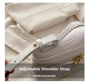 Detail of adjustable white crocodile texture shoulder strap with gold metal buckle