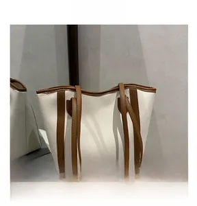 Detail view of cream and brown tote bag with contrast straps on a minimalist setting