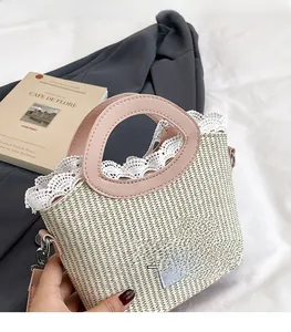 Detailed view of straw bucket bag with white lace trim and pink ribbon bow decoration