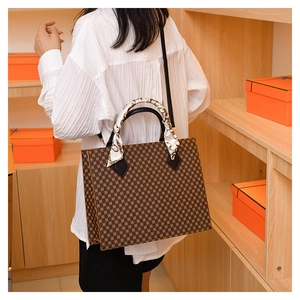 Detail of vintage plaid tote bag with silk scarf on handle shown on shoulder