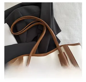 Close-up of the contrast color leather handle and fine stitching on a tote bag