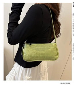 Gros plan du sac baguette vert clair à motif crocodile porté à l'épaule d'une femme
