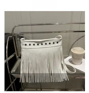 Détail du sac à bandoulière blanc à franges avec clous métalliques sur étagère