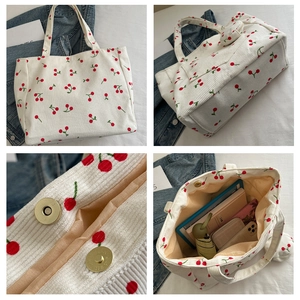 Detail of white corduroy tote bag with cherry embroidery and magnetic metal closure
