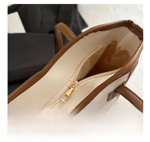 Detailed view of smooth metal zipper and brown synthetic leather trim on the beige tote bag