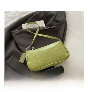 Detail of green crocodile embossed faux leather underarm bag with fashion tag