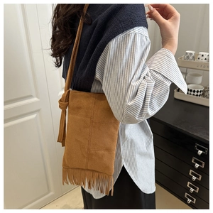 Detail of a brown suede tassel crossbody bag showing fringe texture and knot strap