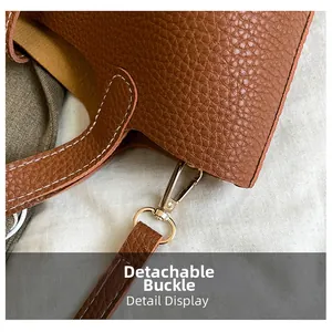 Detail display of detachable light gold buckle on brown lychee grain leather shoulder bag