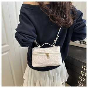 Detail of white woven texture crossbody bag with double zippers and golden hardware