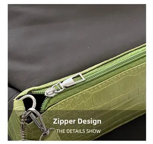 Detail shot of smooth silver zipper closure on green crocodile embossed leather bag