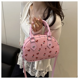 Detailed close-up of pink cherry print bowling bag with silver hardware and dual handles