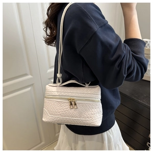Detail of white woven texture handbag with gold double zippers and structured box design