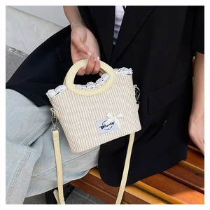 Detail of beige straw handbag with white lace trim and adjustable leather shoulder strap
