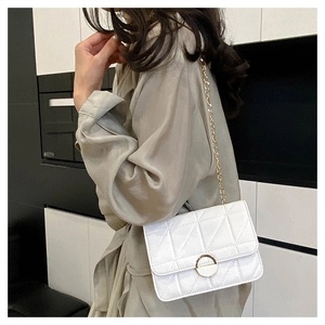 Side view of model wearing a white quilted chain crossbody bag with metal buckle