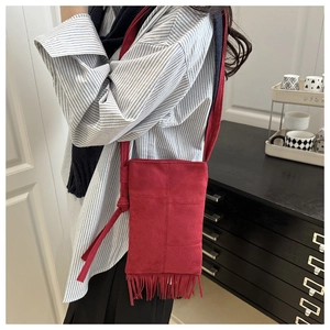 Detail of red faux suede crossbody bag featuring long fringes and bohemian knot accents