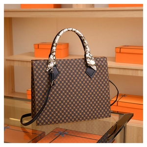 Close-up of brown geometric tote bag featuring silk scarf handle and leather shoulder strap