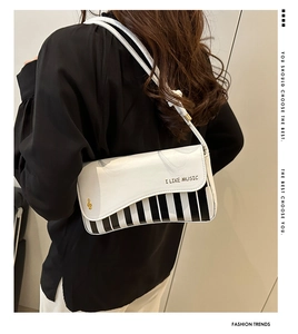 Detail of piano-themed shoulder bag featuring black and white keys and musical notes