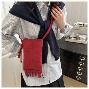 Detail of red crossbody bag featuring long fringes and textured suede-like finish