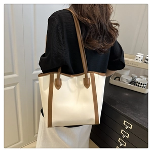 Detail view of the cream and brown PU leather tote bag worn by a model in a home setting