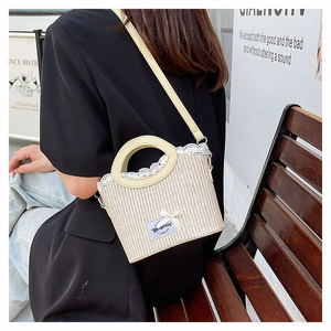 Detail of hand-woven straw bag featuring delicate lace trim and PU leather top handle