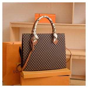 Detail of geometric pattern tote bag with silk scarf handle on orange boxes