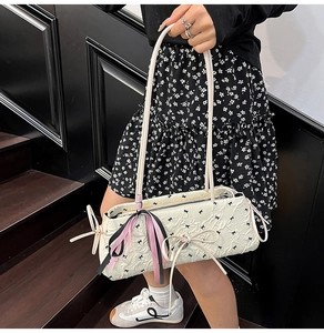 Dettaglio della borsa plissettata bianca con motivo a fiocchi e nastro rosa decorativo