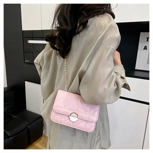 Pink quilted crossbody bag with gold chain strap shown on model in a modern interior
