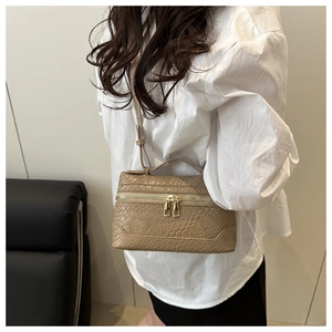 Detailed view of beige crocodile embossed handbag with gold zippers and dual carry options