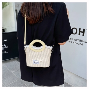Détail du sac en paille tissé à la main avec dentelle blanche et poignée ronde en extérieur