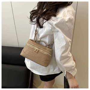 Detailed side view of a light brown crocodile embossed handbag with gold-tone hardware
