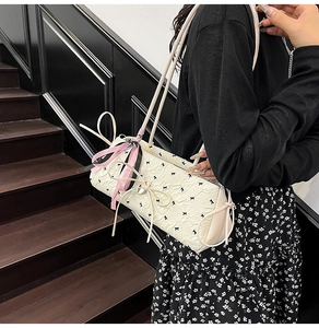 Dettaglio della borsa baguette color crema a pois con nastri di raso rosa