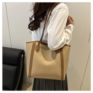 Chic beige and brown leather tote bag carried by model in a minimalist setting