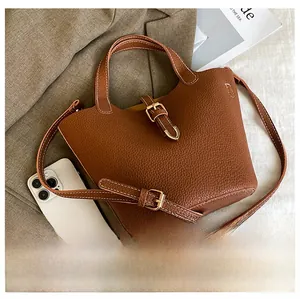 Brown litchi grain bucket bag detail with gold buckle and smartphone for scale